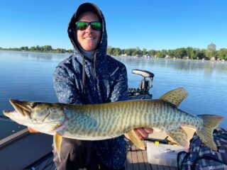 a happy angler on his boat with a beautiful clearwater muskie