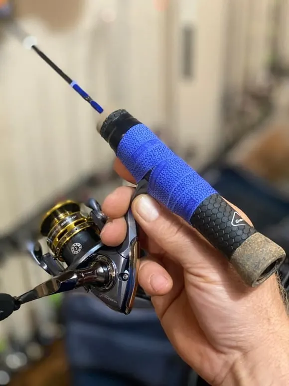 an angler holding an ice fishing rod with a pflueger sp20 reel