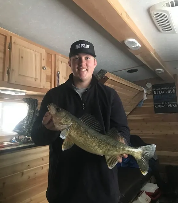 A happy angler in an ice house on Mille Lacs Lake holding a nice walleye