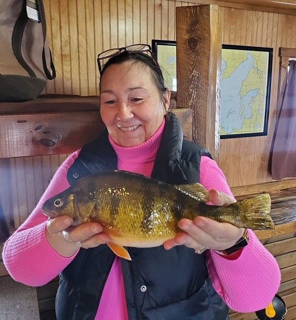 a female angler in an ice house on Leech Lake holding a fat yellow perch