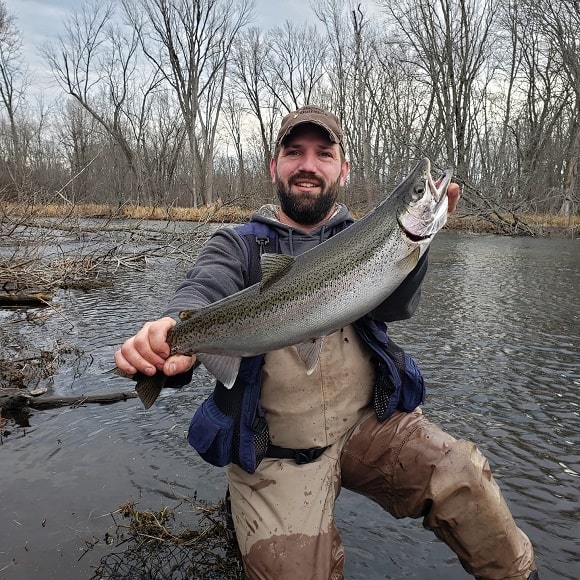 a happy angler holding a big steelhead that he has caught on the Muskegon River