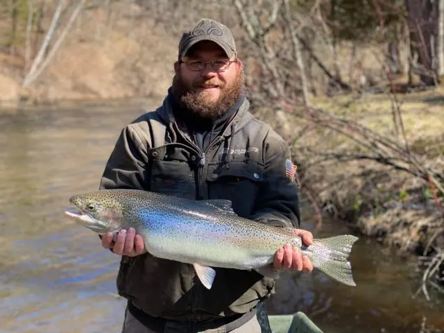 a trout angler with a beautiful steelhead on the Salmon River in New York