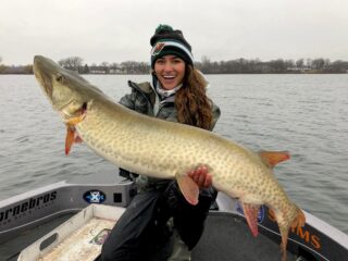 Nattie up North on her boat holding a giant Minnesota musky