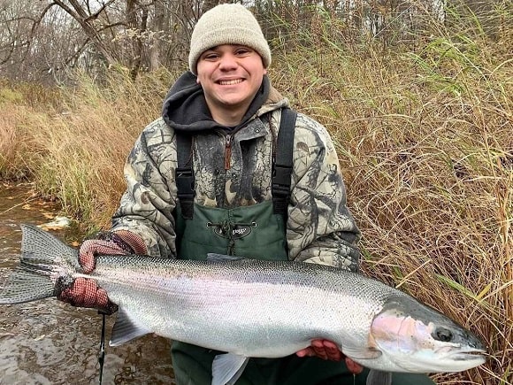 a fisherman holding a giant steelhead caught on a New York river
