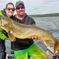 a fishing couple on a boat with a giant lake trout that they caught jigging