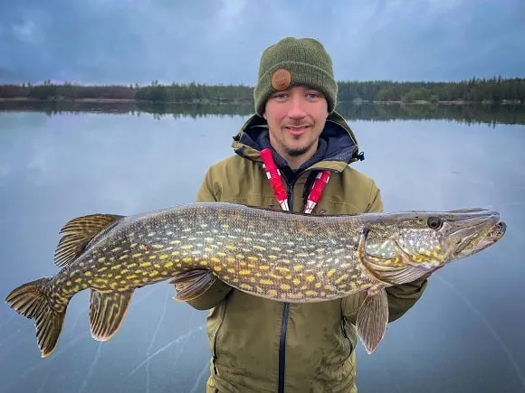 a YouTube angler on the ice holding a nice northern pike
