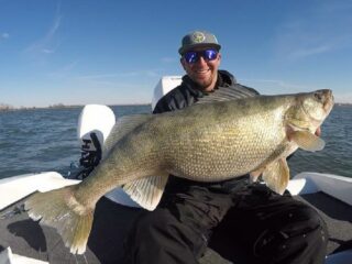 a predator angler on his boat holding a giant pre-spawn walleye