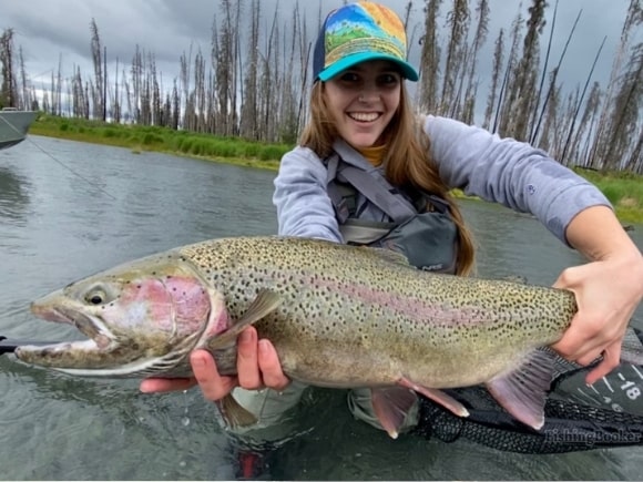 a female trout angler on a river with a giant alaska steelhead
