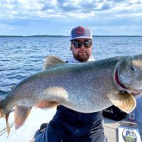 a happy angler on his boat with a giant north Canadian lake trout