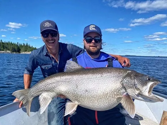 two anglers on a lake with an absolutely enormous and very fat lake trout