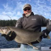 a trout angler on his boat holding a gaint pre-spawn lake trout