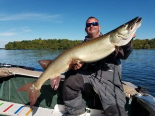 a happy predator angler on his boat with a massive musky