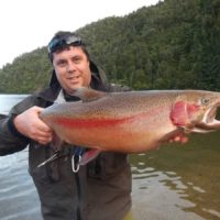 a happy fly fisherman on a river with a giant rainbow trout