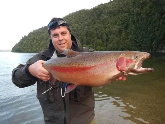 a happy fly fisherman on a river with a giant rainbow trout