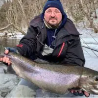 a trout angler on a river with a giant winter-run steelhead