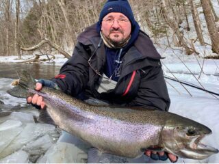 a trout angler on a river with a giant winter-run steelhead