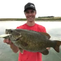 a happy angler on a lake with a giant smallmouth bass