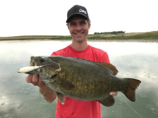 a happy angler on a lake with a giant smallmouth bass