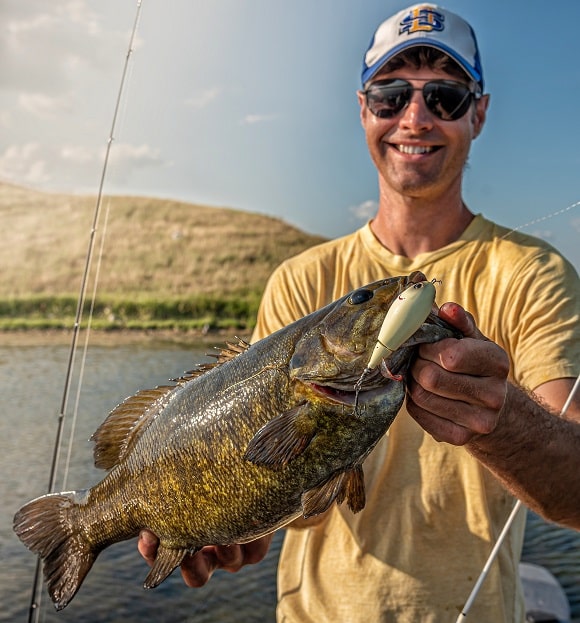 an angler on his boat holding a heavy pre-spawn smallmouth bass female
