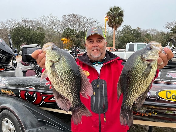 a happy angler holding two trophy sized crappie