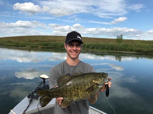 a happy bass angler on a lake with a big trophy smallmouth