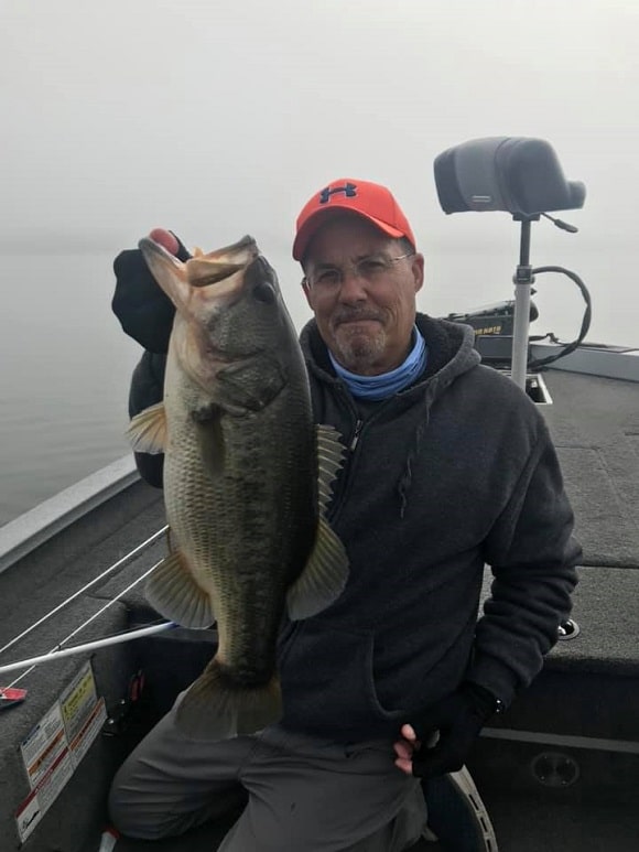 a bass angler on a lake with a really big largemouth bass caught just before spawning