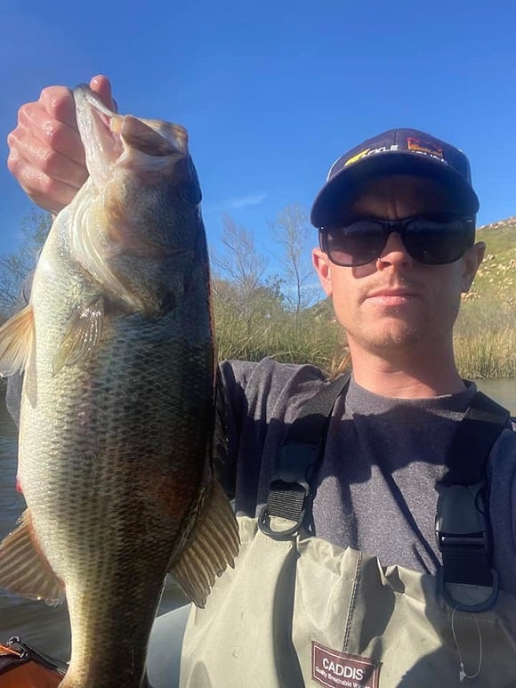 a bass angler holding a largemouth bass caught during the spawning season