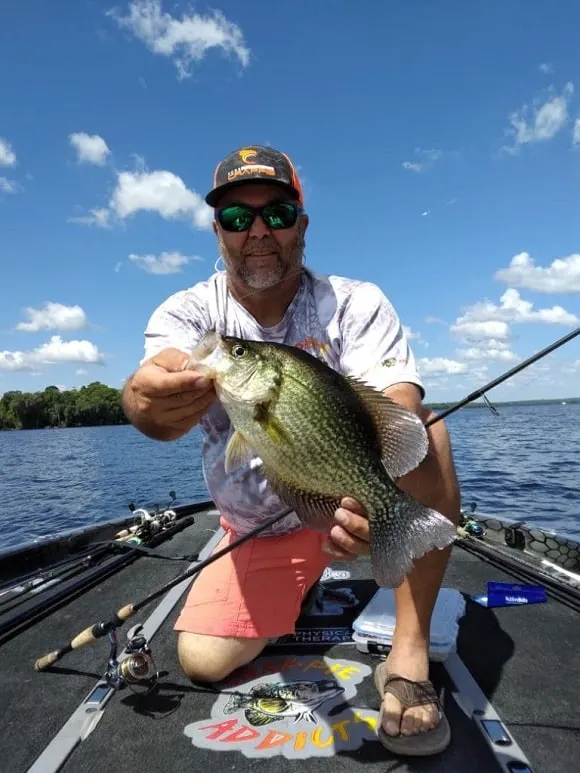 a Floridian angler on his boat holding a very big black crappie caught on Lake Toho