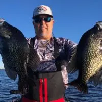 a crappie angler in Florida holding two big black crappies