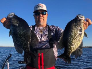 a crappie angler in Florida holding two big black crappies