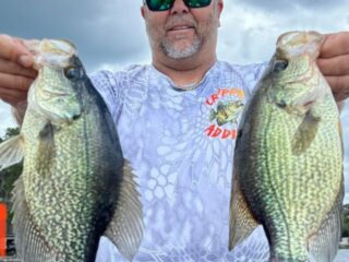 a happy angler holding two big crappie slabs