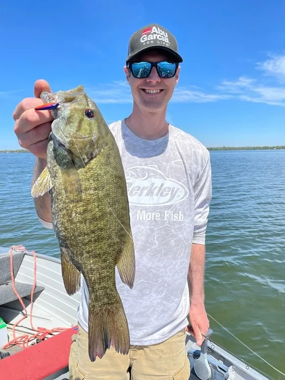a happy bass angler on a boat with a really big smallmouth bass
