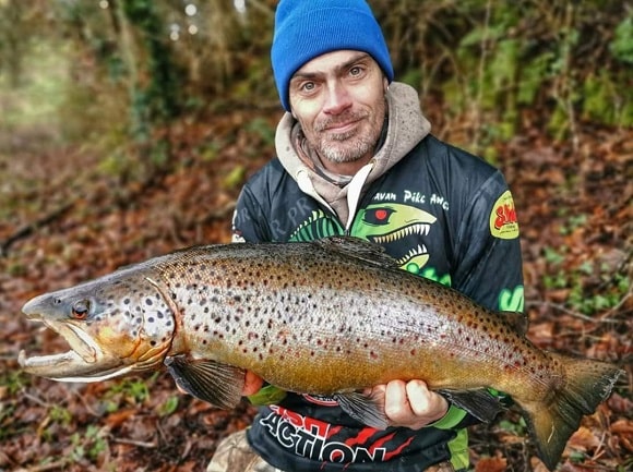 a trout angler on a lake in England with a big and fat brown trout