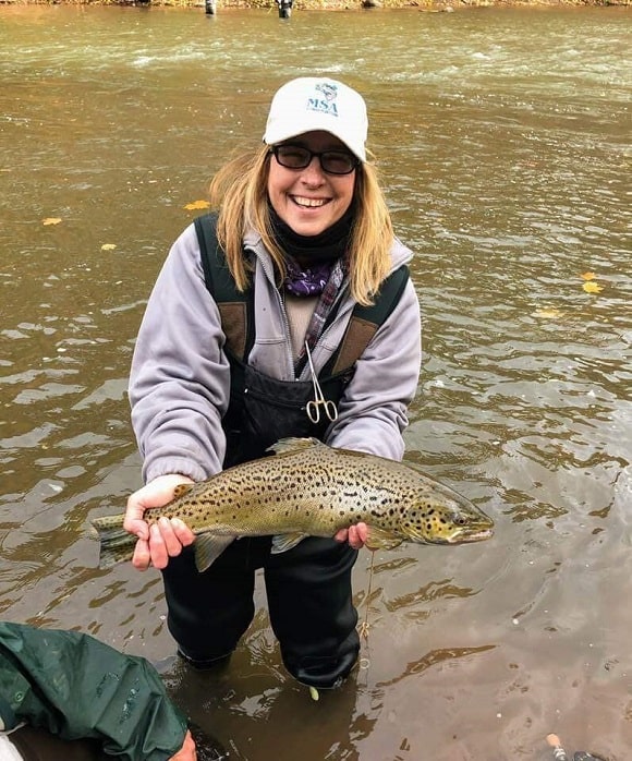 a happy female angler with a big brown trout caught in cold water