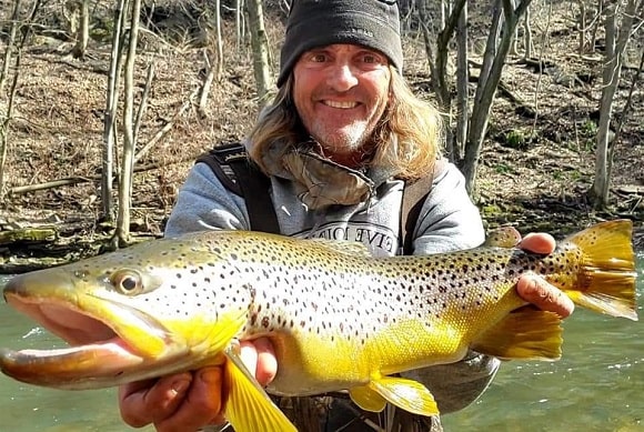 a happy US trout angler with a colorful brown trout caught  during the spawn