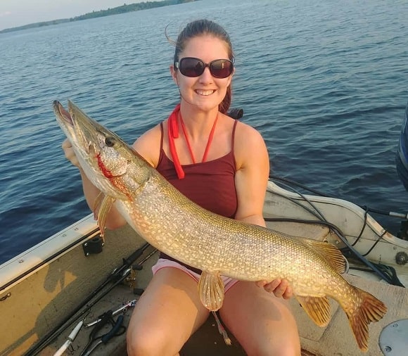 a Canadian angler on a baot holding a good-sized northern pike