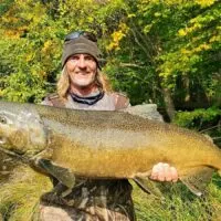 a happy river angler holding a huge king salmon