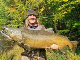 a happy river angler holding a huge king salmon