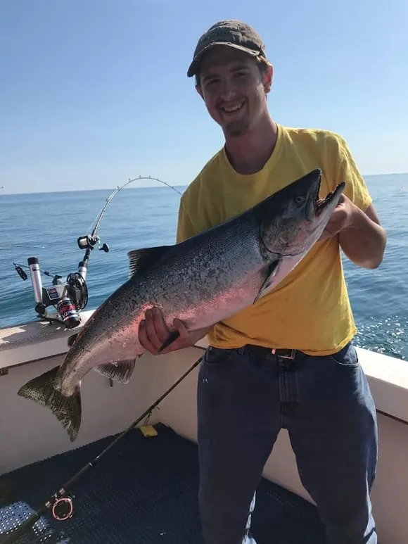 a trolling angler on a lake with an average sized salmon