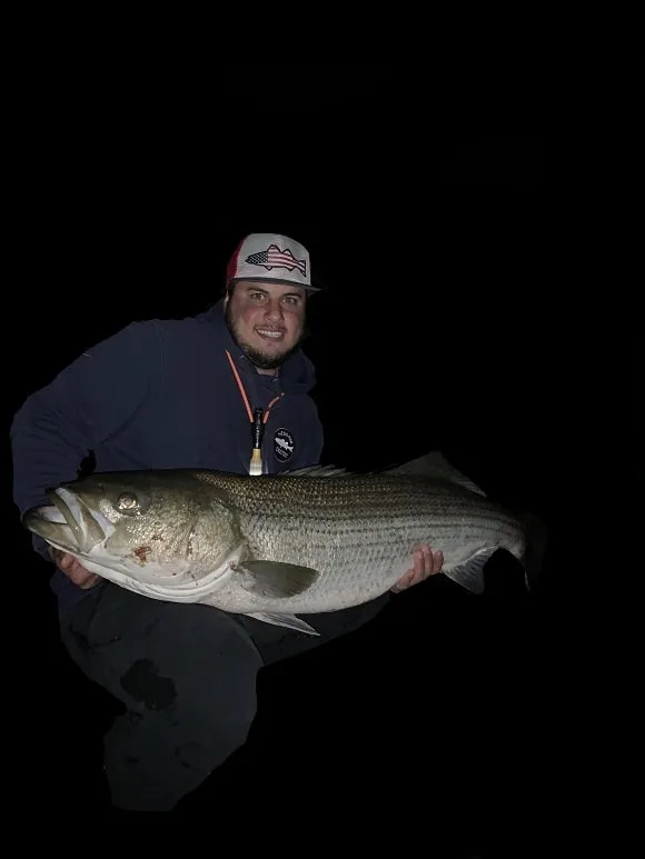 a night angler in Connecticut holding a huge striped bass