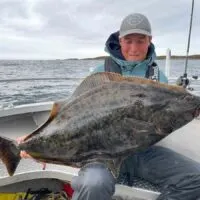a happy angler fishing for giant halibut in Norway