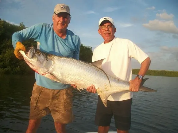 two anglers on a boat holding a trophy-sized tarpon