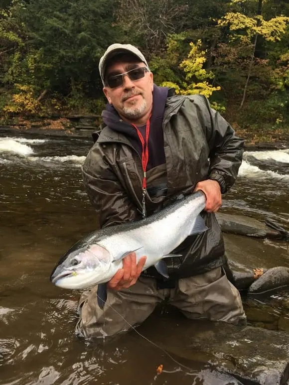 a happy trout angler on a river holding a big Oregon steelhead