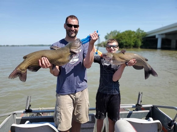 a father and his son fishing for channel catfish on a river