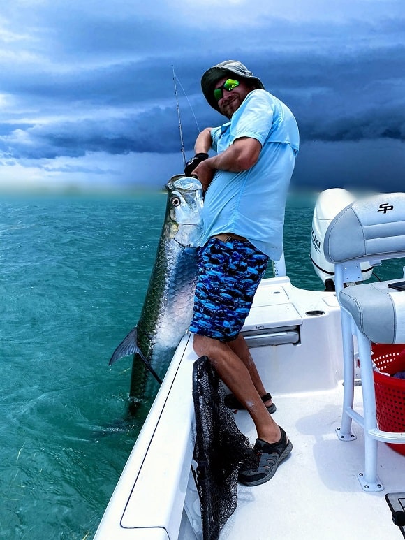 a Florida saltwater angler on his boat trying to lift a gigantic Atlantic tarpon