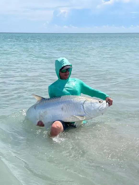 an angler in shallow water releasing a giant tarpon