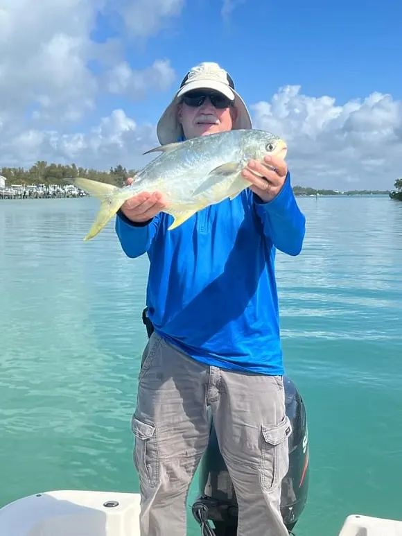 a happy saltwater angler on his boat holding a big pompano