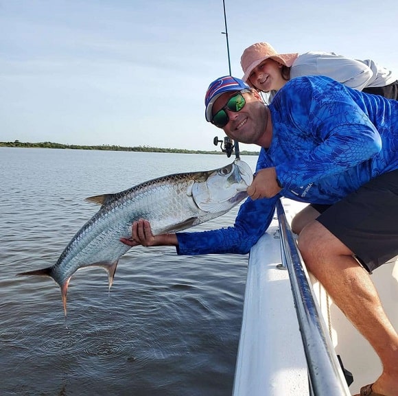 a happy angler on a boat with a nice tarpon