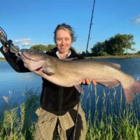 a happy female angler holding a big pre-spawn channel catfish