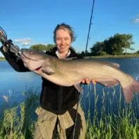 a happy female angler holding a big pre-spawn channel catfish